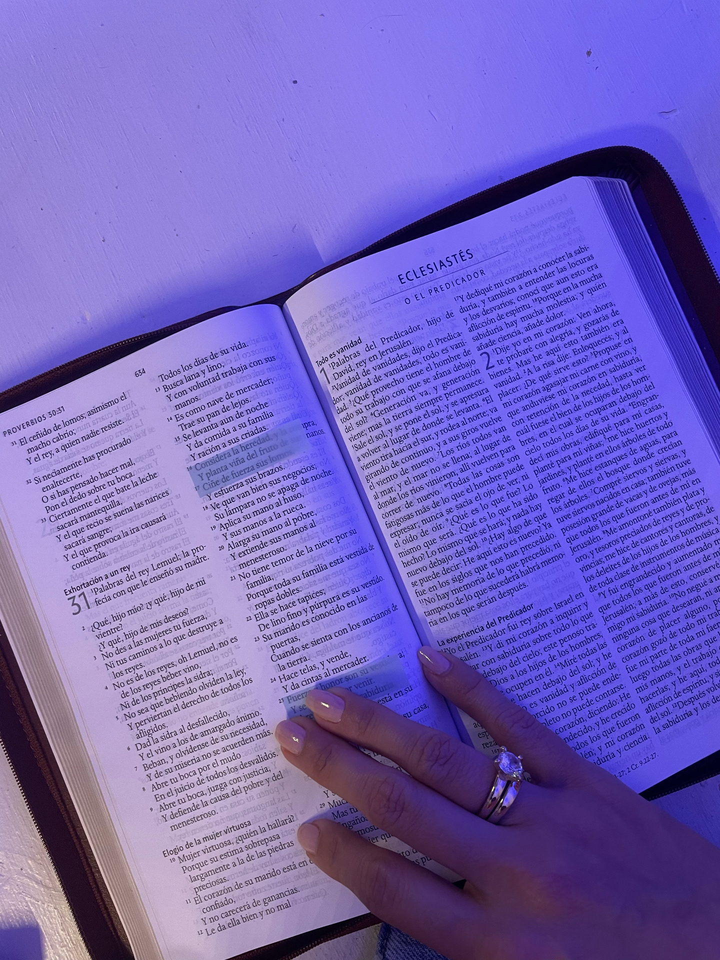 Biblia abierta en Proverbios y Eclesiastés, con una mano descansando sobre las páginas